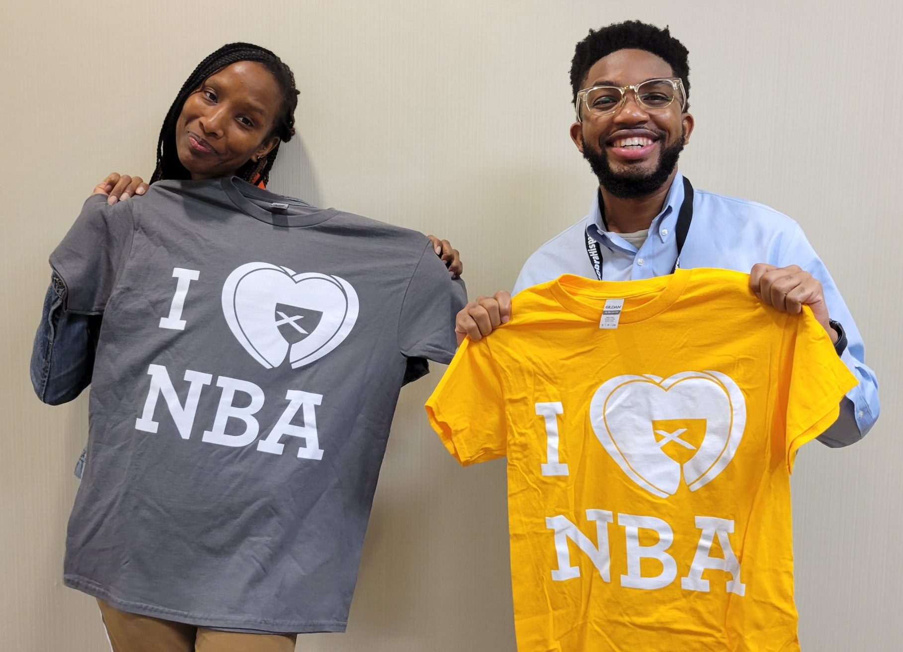 Rev. Rae Karim, Interim Director of NBA's Young Adult Programming and Reginald Warren hold up 'I Love NBA" shirts.